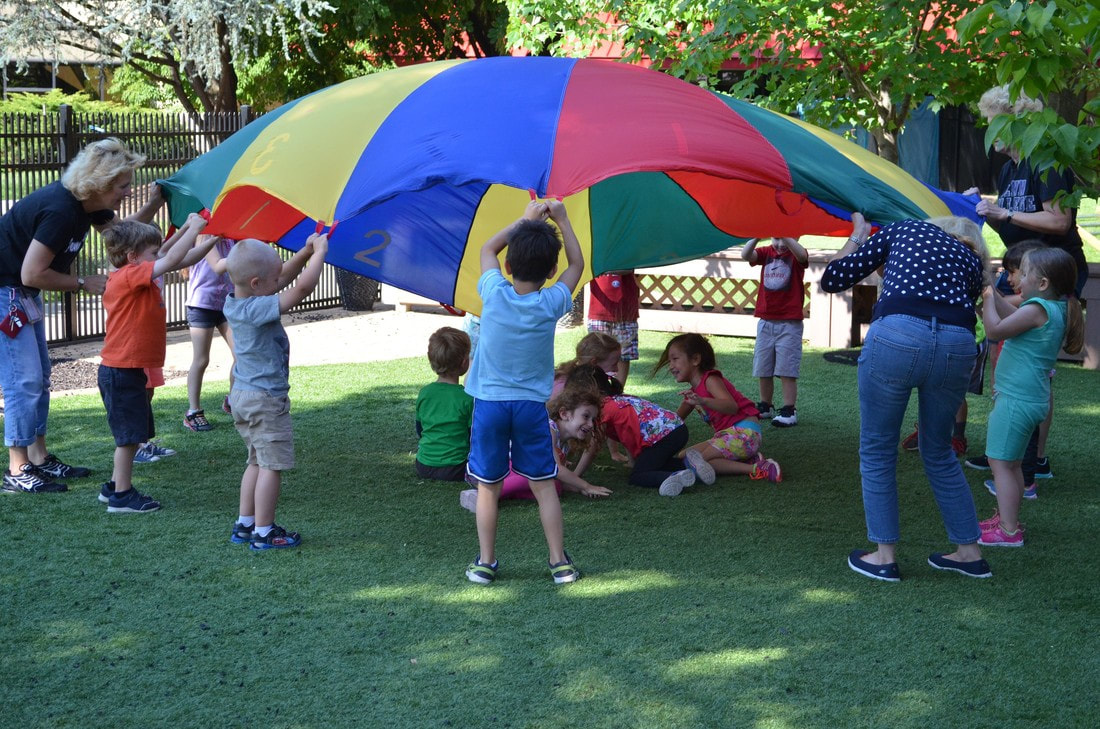Image adults and children playing with a parachute